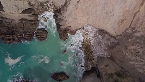 volando hacia arriba y lejos de la playa de guijarros rocosos con olas en la costa de california cerca de la autopista uno