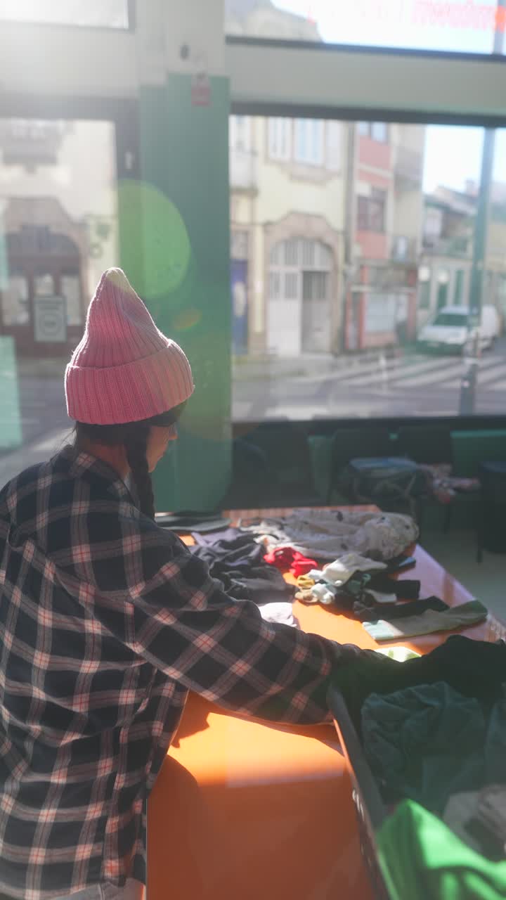 mujer clasificando ropa donada en un centro de caridad