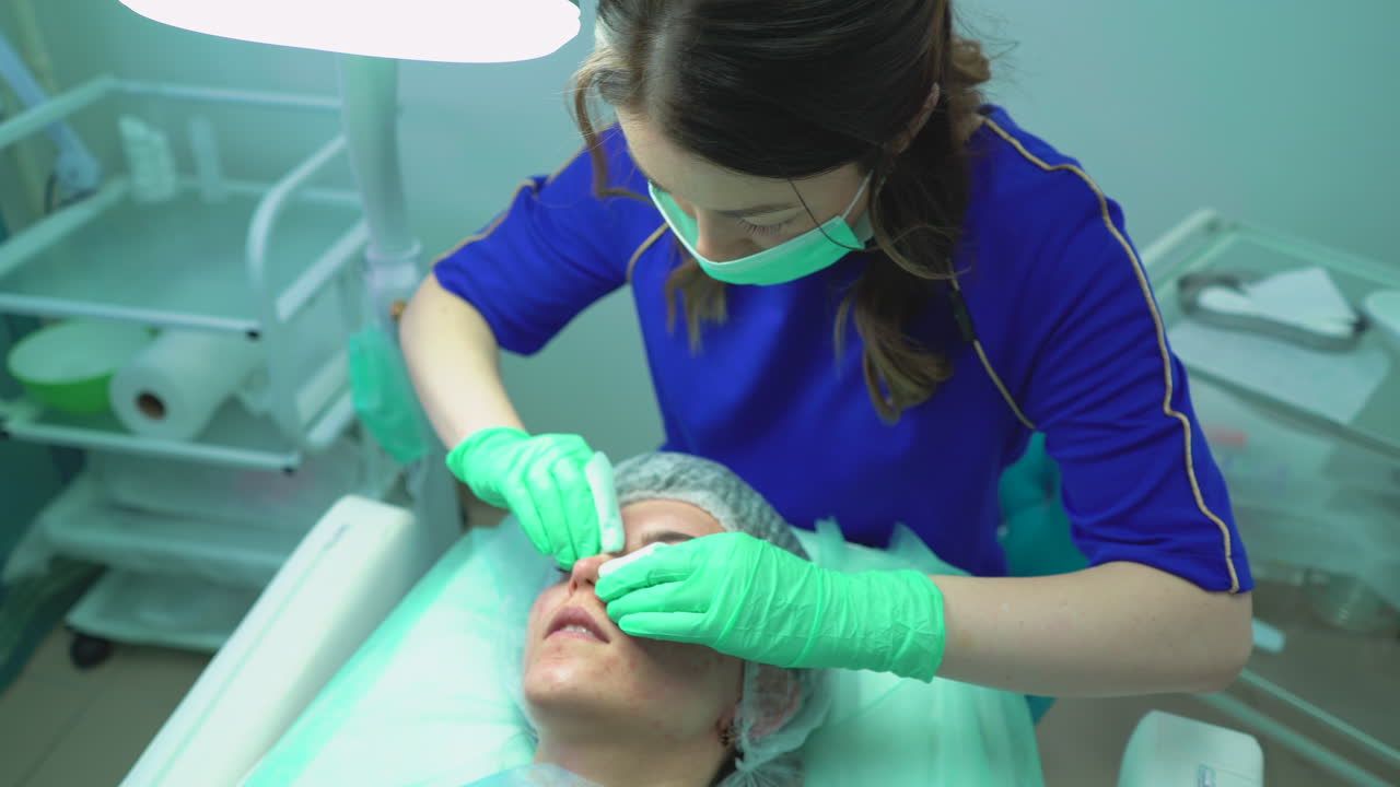 un cosmetologo schiaccia i brufoli sul viso di un giovane cliente in un salone di bellezza