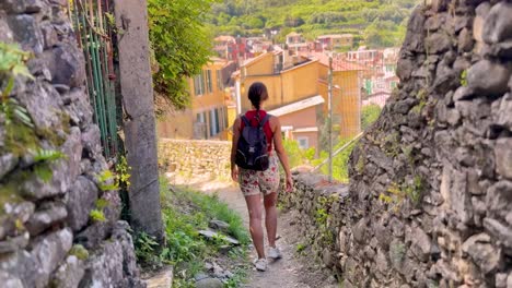 young woman walking through picturesque streets of cinque terre, italy – rear view in colorful mediterranean village