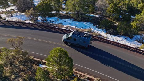 vehículo recreativo conduciendo a través de la carretera en el denso bosque nevado cerca del parque nacional del gran cañón en arizona, ee.uu.