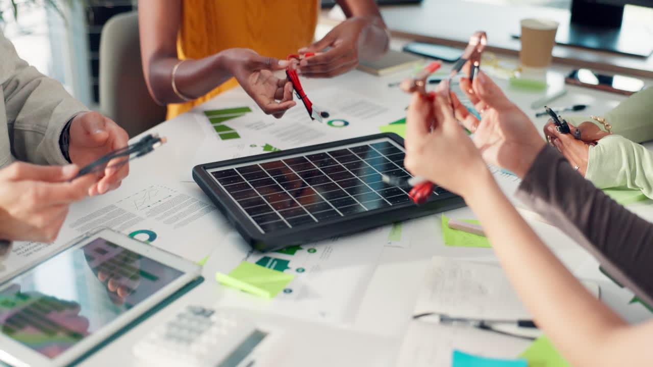 Business Team Examining a Small Solar Panel and Electronic Components