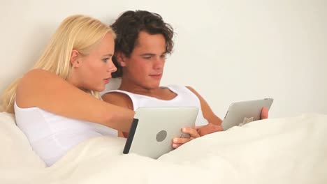 Couple-with-tablets-in-their-bed
