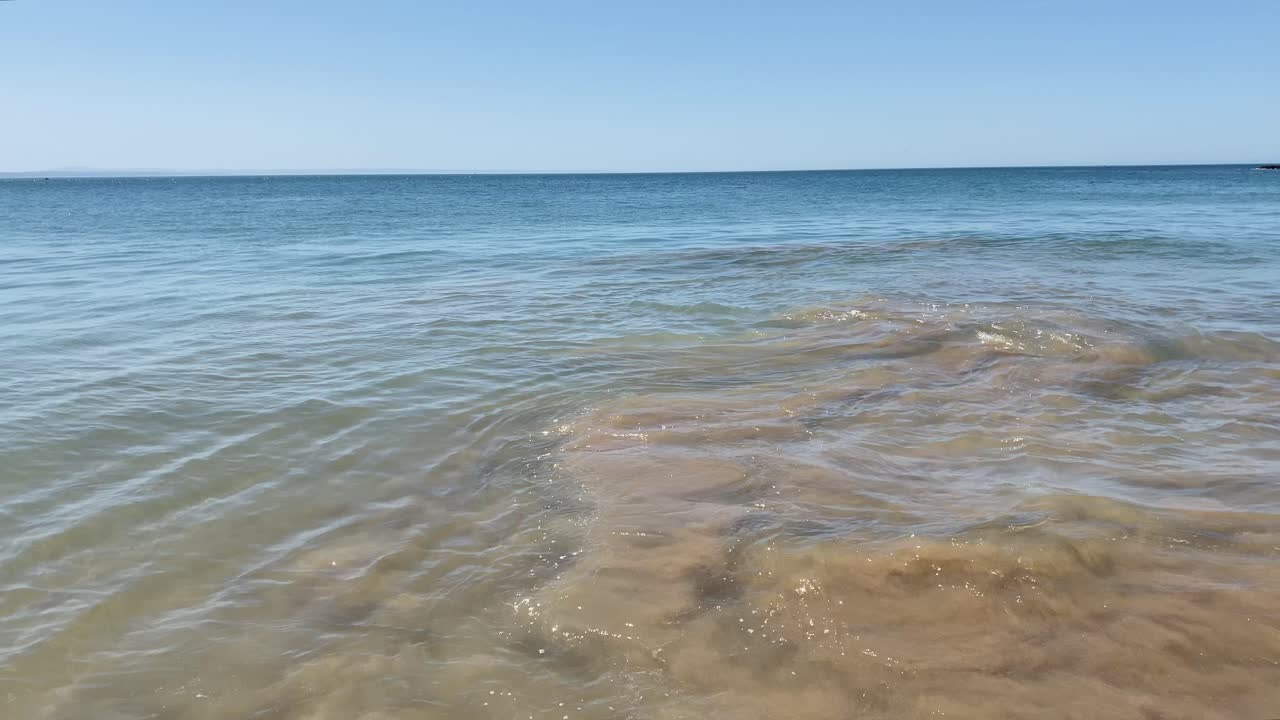 유럽 해변의 해안 근처의 바다에서 부드럽게 굴러가는 작은 파도