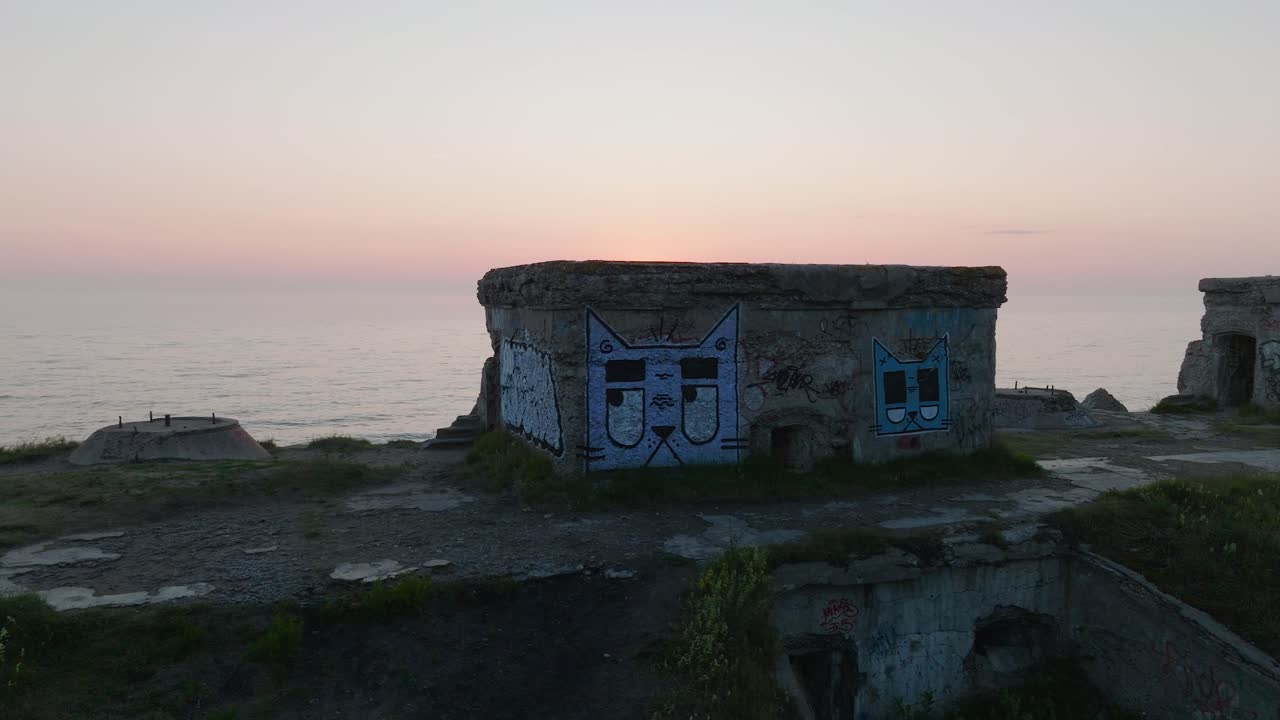 hermosa vista aérea de un atardecer vibrante de alto contraste sobre el tranquilo mar báltico, nubes en el horizonte, el puerto de guerra de karosta, la costa de hormigón, las ruinas de la fortificación en liepaja, un amplio drone dolly disparado moviéndose a la izquierda