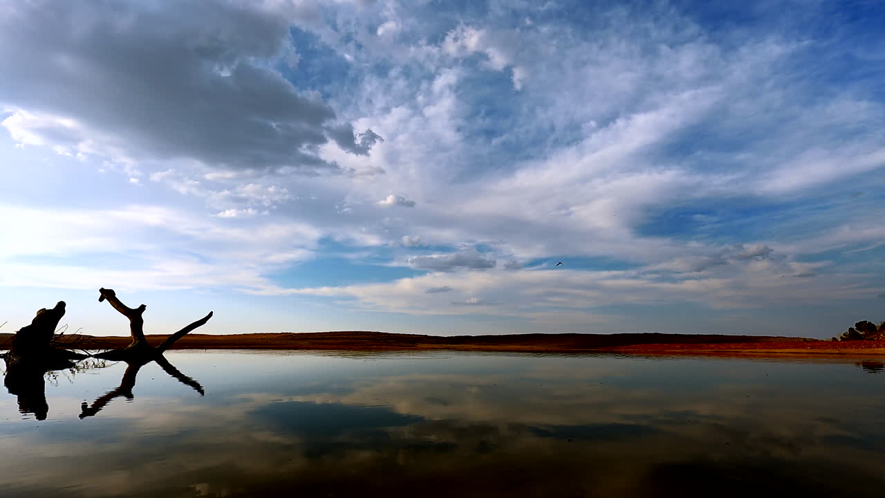 Time-lapse of sunset clouds over water hole in Africa, sun set time