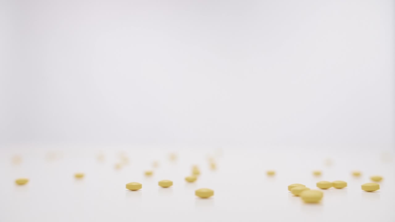 pastillas amarillas cayendo sobre fondo blanco en cámara lenta