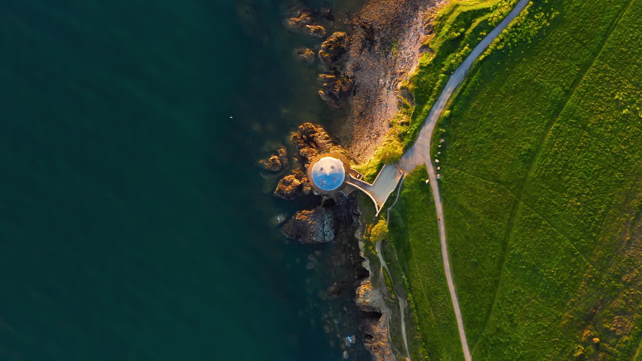 Aerial Stationary Top Down View of Martello Tower With Cyclist Passing By During Golden Sunset