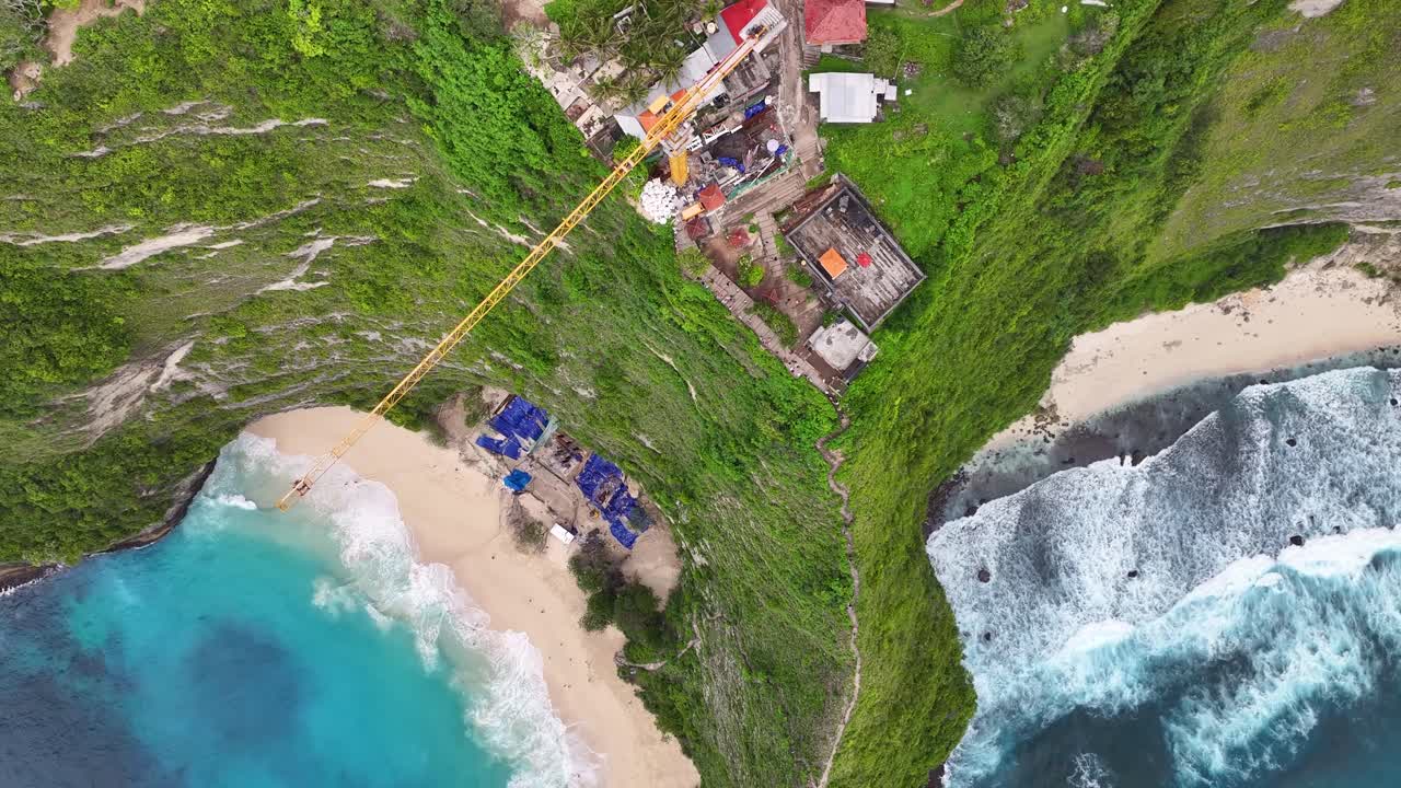 Crane operation over Kelingking Beach, controversial construction project for boost tourism. Drone