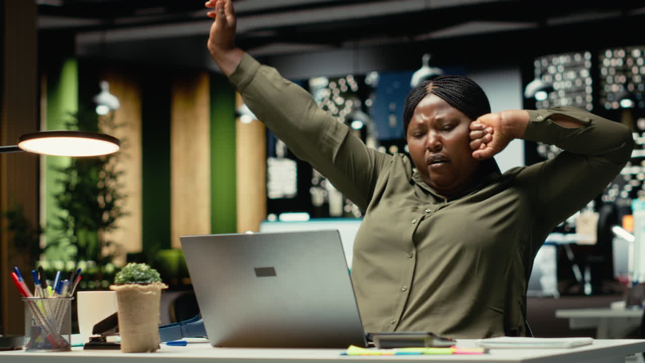 Female office worker managing daily tasks at night with focus music on headset
