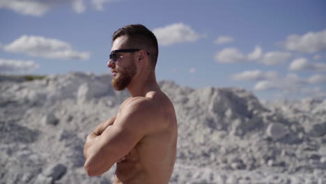 fitness male model posing. handsome bearded bodybuilder man with perfect muscular body posing outdoors