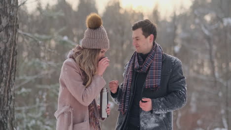 a caring man warms his wife's hands in the winter on the street in a snow-covered park