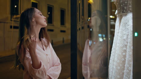 girl watching bridal dress on mannequin standing store showcase close up.