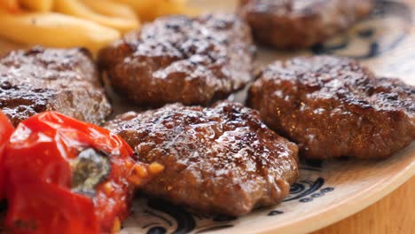 close up of grilled meatballs with tomatoes and french fries on a plate