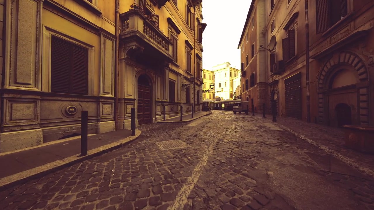 Tranquilla strada acciottolata con facciate invecchiate sotto la luce soffusa del tramonto.