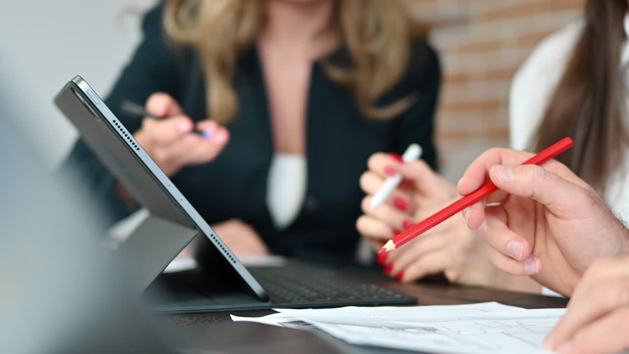 Coworkers analyzing a building plan on a tablet at a table in an office