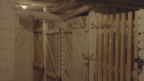 un pasillo flanqueado por múltiples puertas de madera con barras, lo que sugiere una mazmorra o una atmósfera de prisión histórica