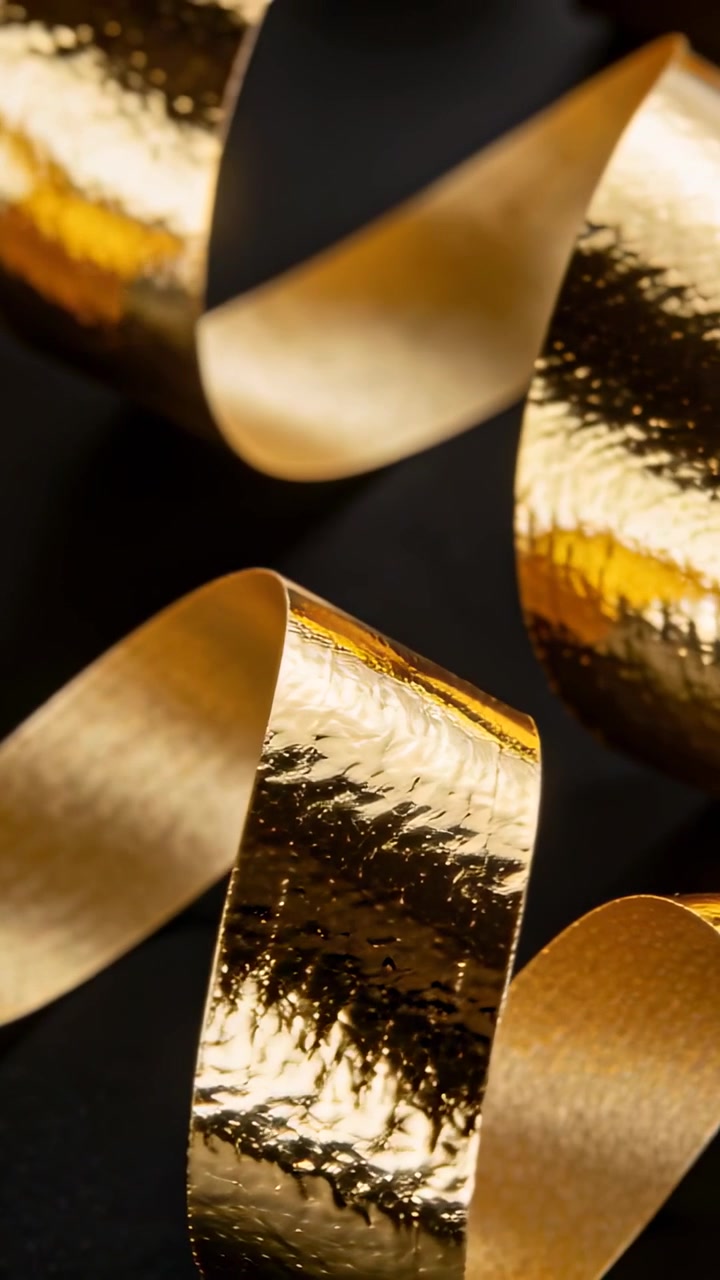 Video verticale: Panoramica della telecamera che muove nastri d'oro, ruotando e rivelando una texture martellata in studio
