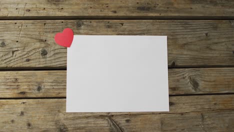 Paper heart and white card with copy space on wooden background at valentine&#039;s day
