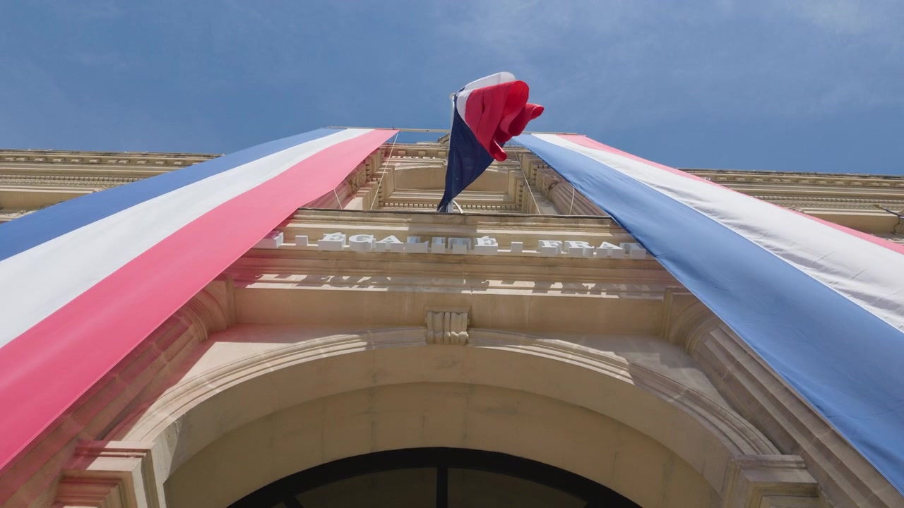 Close view of a large French flag banner whipping in the wind on a building facade, Cannes, France