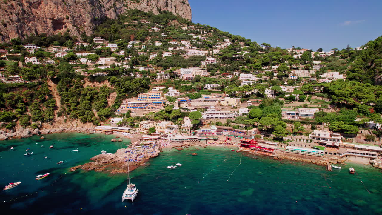 아말피 해안을 따라 이탈리아에서 인기 있는 고급 휴양지인 유명한 섬 카프리의 마리나 피콜라 주변의 멋진 풍경을 드러내기 위해 뒤로 물러나는 부드러운 드론 샷