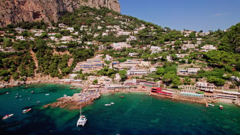 una suave toma de drones retrocede para revelar el impresionante paisaje alrededor de marina piccola en capri, una famosa isla que es un popular destino de vacaciones de lujo en italia a lo largo de la costa de amalfi