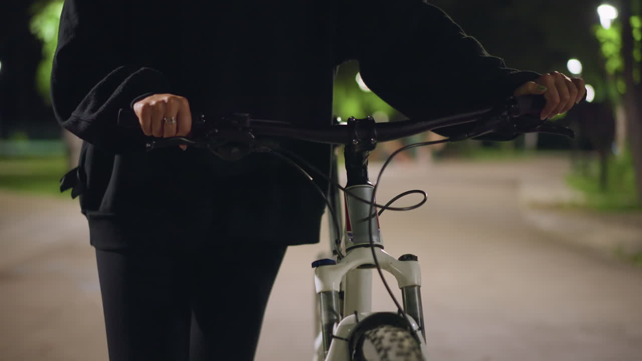 Solitary Cyclist Under Gentle Lighting, Lone Rider On Tranquil Path Beneath Soft Glowing Lights, Solitary Cyclist Pauses On Peaceful Night Trail With Calm Surroundings And Gentle Illumination