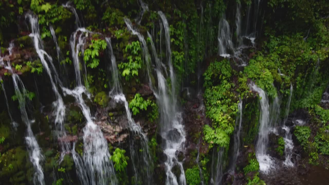 Drone footage of Banyu Wana Amertha Waterfall in Bali. Lush tropical jungle, cascading water, and peaceful natural scenery.