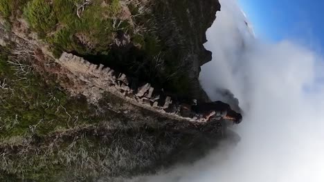 vertical 360 footage of a man standing on a stone wall on top of pico do jorge in madeira