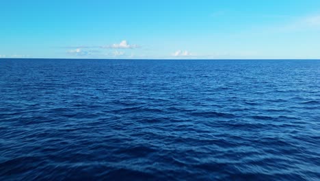Gentle aerial over open ocean with tranquil blue water and soft horizon, ideal for peaceful backgrounds