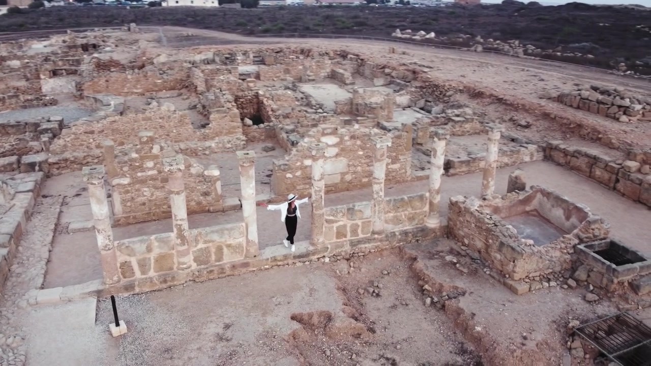 Vista aerea di un sito archeologico con antiche strutture in pietra e una persona che esplora le rovine.