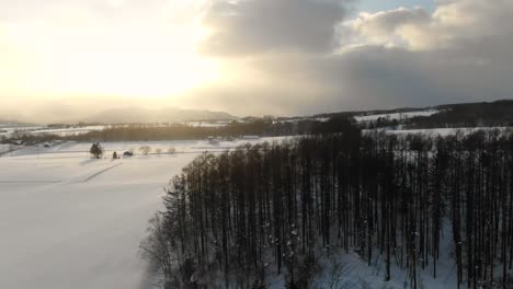 Imágenes-De-Drones-De-4k-De-Campos-Nevados,-árboles,-Montañas-Y-Pueblos-En-La-Ciudad-Rural-De-Esquí-De-Niseko,-Japón,-Durante-La-Puesta-De-Sol-Y-La-Hora-Dorada