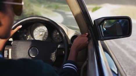 Mujer-Afroamericana-Ajustando-El-Espejo-Retrovisor-Mientras-Conduce-En-Un-Coche-Convertible