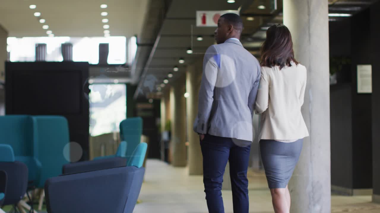 Compañeros de trabajo caminando, mujer sosteniendo un dispositivo que activa gráficos animados y revisando datos