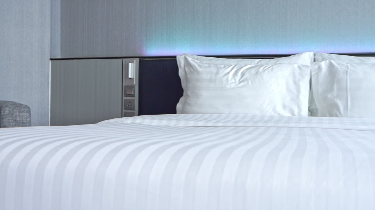 cama doble con sábanas y almohadas blancas en la habitación del hotel