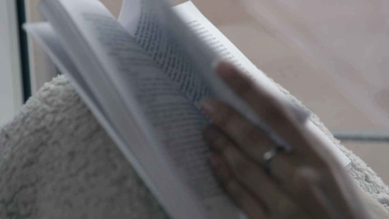 Close-up of Hand Turning Pages While Reading a Book