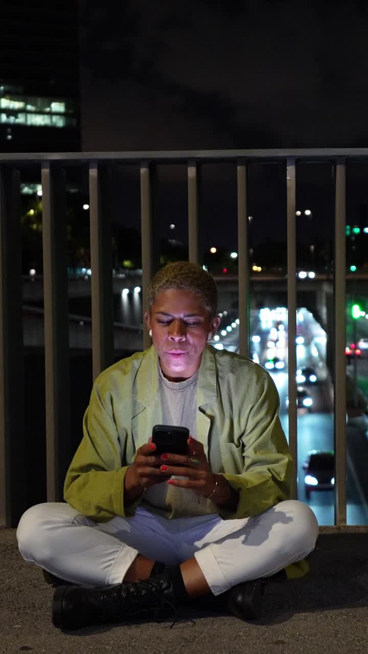 Giovane donna che usa lo smartphone di notte su un ponte cittadino