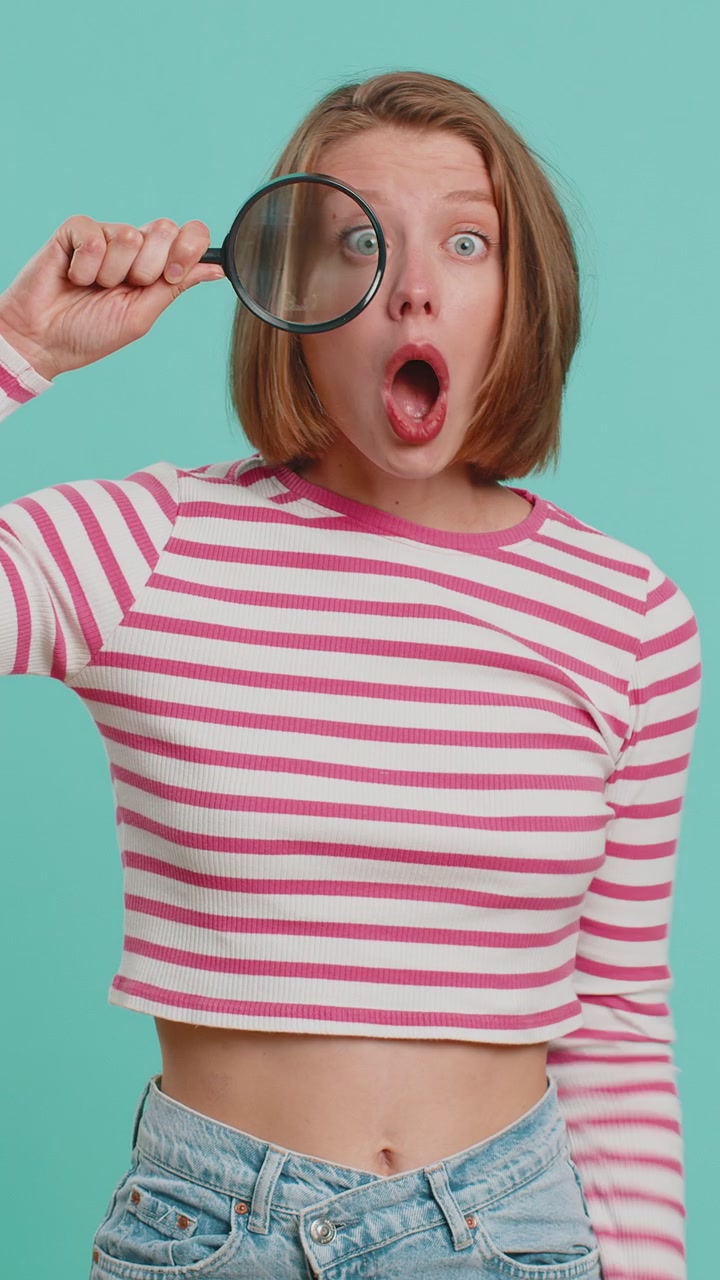 Investigator researcher woman with magnifying glass near face looking into camera with big zoom eye