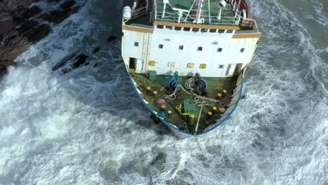 big waves crashing into a cargo shipwreck and rocks on ireland’s south coast