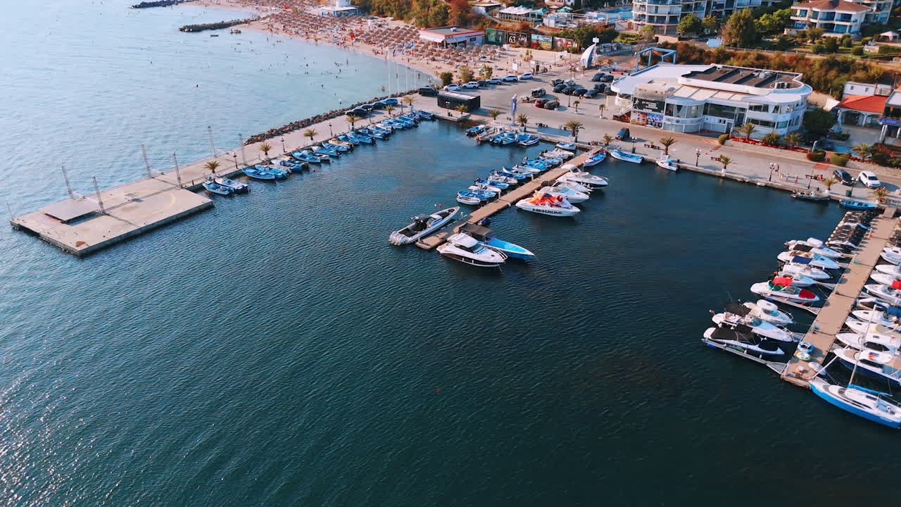 Summer boats at a lively marina. A variety of boats are moored at a bustling marina on a sunny day near a seaside town