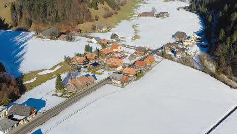 瑞士伯恩州 (canton of bern) 的埃姆曼塔爾 (emmental) 一座小村莊的無人機拍攝,顯示小鎮的建築,以及家園和周圍的雪山