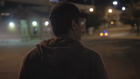 view from behind of a man walking down a city street at night