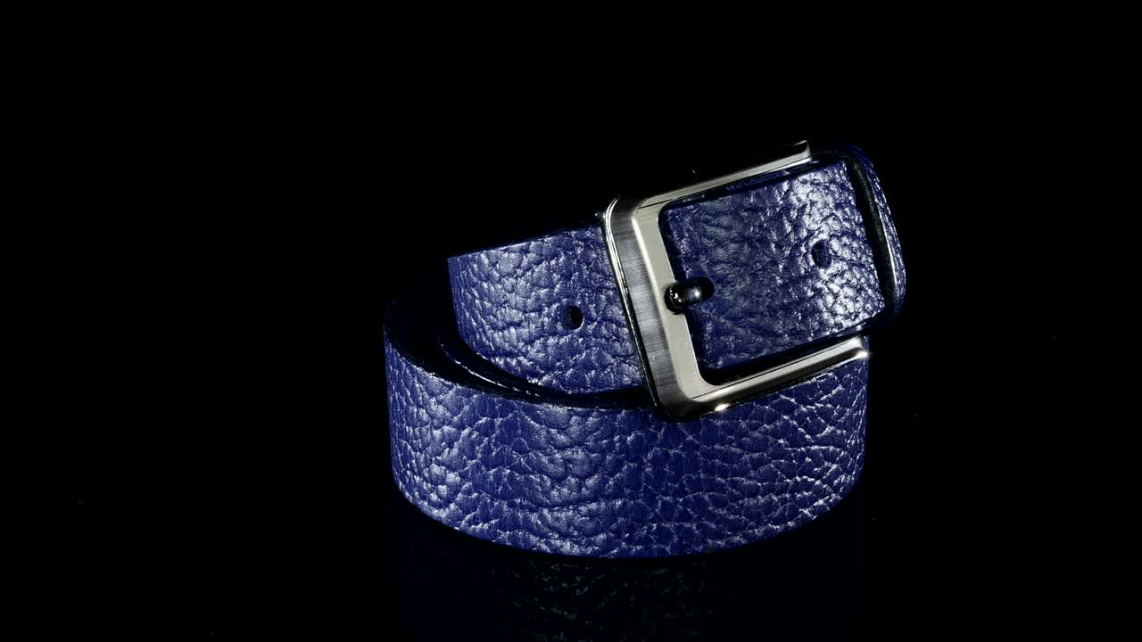 파란색 남성 벨트는 검은색 배경에 회전합니다.