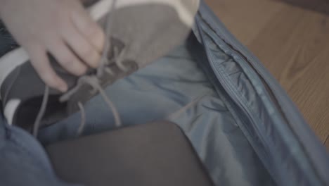 close up empty suitcase, man putting sport shoes, static shot