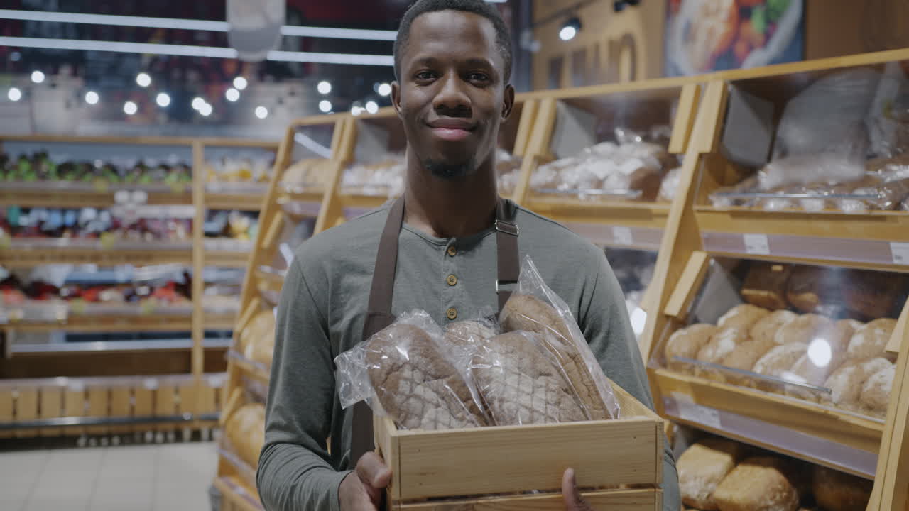 Freundlicher Bäckereimitarbeiter hält eine Brotkiste