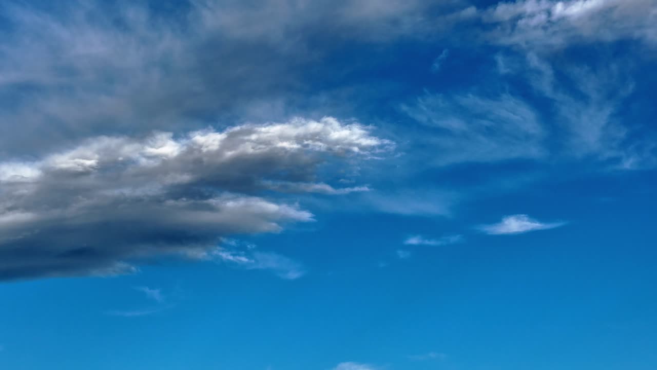 Questo timelapse aereo in 4K con drone segue nuvole bianche in movimento attraverso un orizzonte di cielo blu profondo. Il rapido movimento atmosferico crea uno sfondo naturale pulito e dinamico