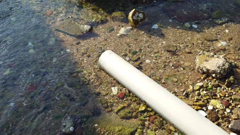 profile view of a pipe excreting out wastes into water during daytime in lei yue mun, hong kong