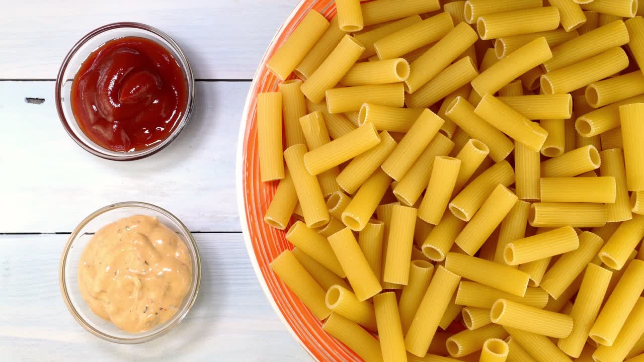 pasta italiana rigatoni cruda sin cocinar girando lentamente en la mesa giratoria en el plato.