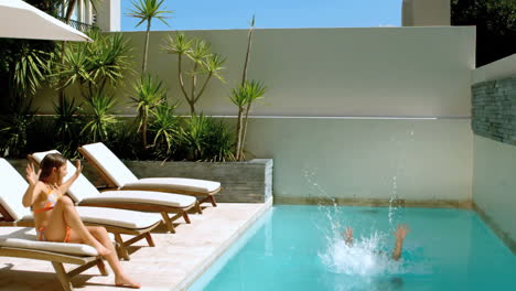 Bruder-Springt-In-Den-Swimmingpool,-Während-Schwester-Ihm-Zusieht