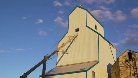 low angle shot of a white grain elevator with setting sun rays falling on it in alberta, canada at sunset